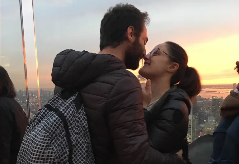Coppia che si bacia dopo la proposta di matrimonio con New York al tramonto sullo sfondo