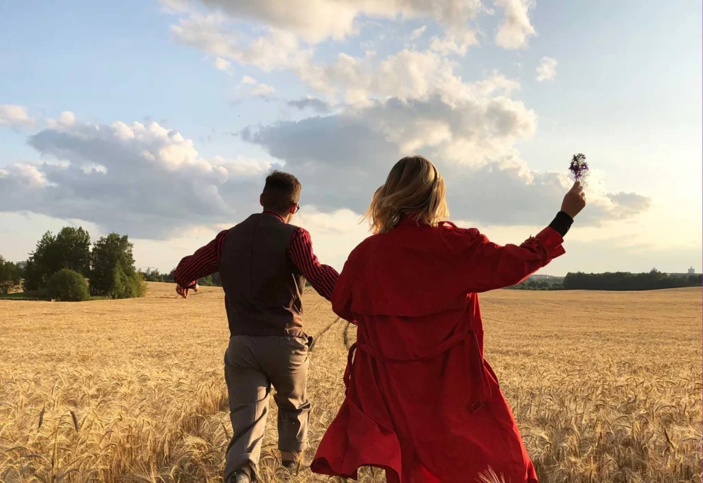 A couple walking through a wheat field at sunset