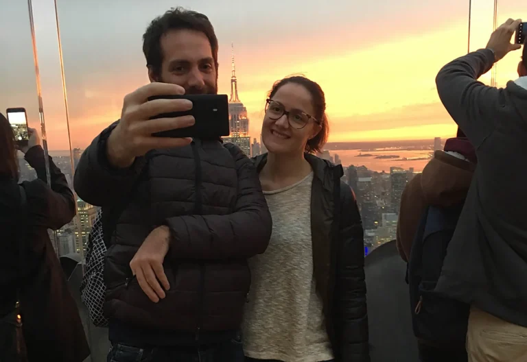 Coppia che scatta un selfie al tramonto con lo skyline di New York sullo sfondo