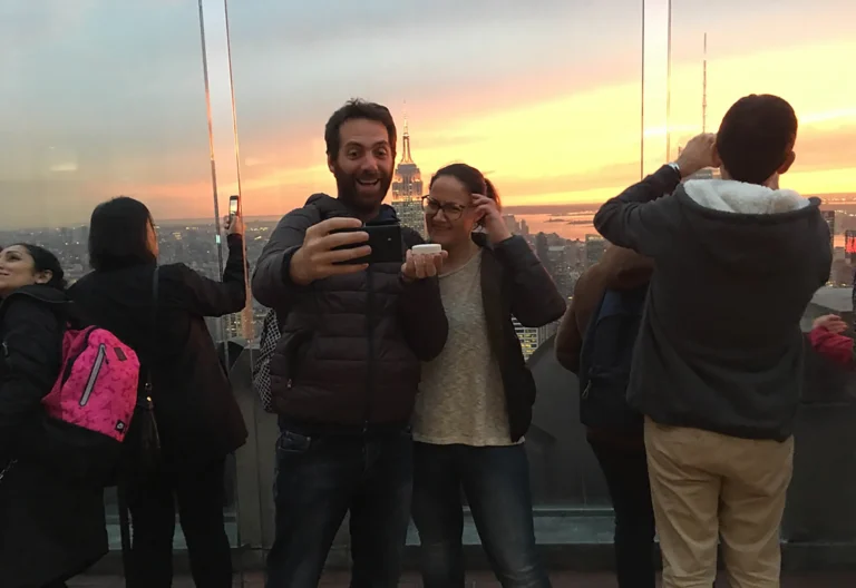 Coppia sorridente dopo la proposta di matrimonio con anello mostrato davanti allo skyline di New York