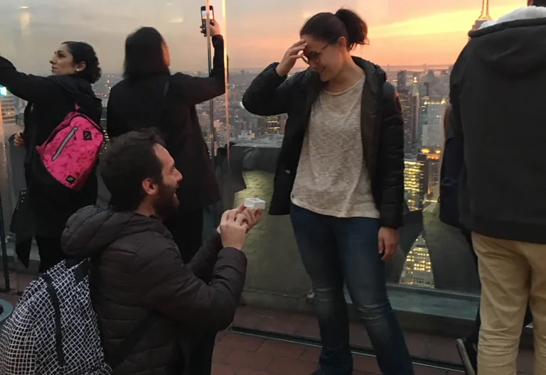 Uomo inginocchiato durante la proposta di matrimonio mentre mostra l'anello alla futura sposa a New York