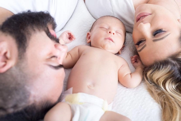 Neogenitori con il loro bambino appena nato, simbolo dell’amore familiare e dei gioielli dedicati alla maternità.