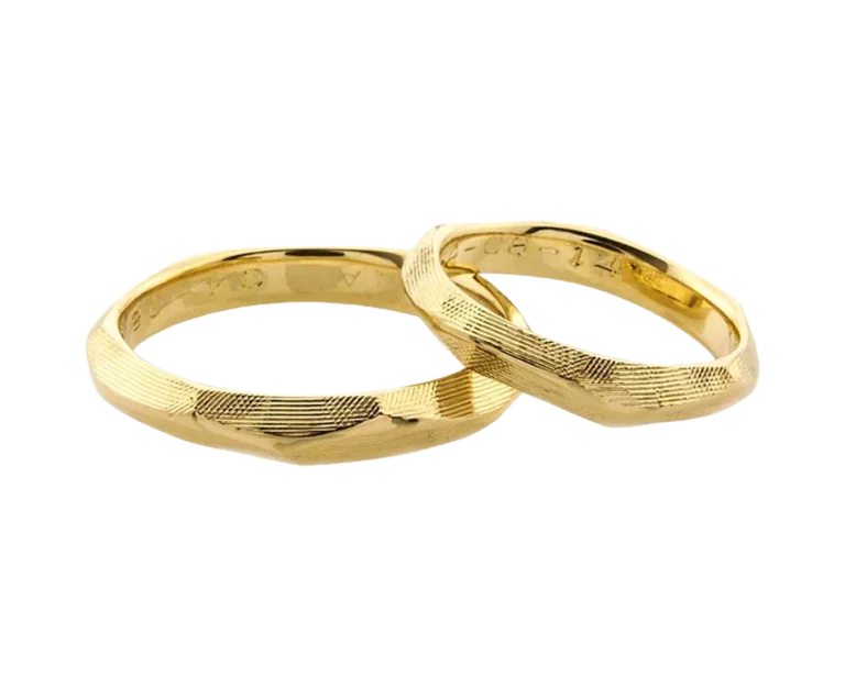 Detail of the yellow gold cross-hatched wedding bands with hand-engraved detailing