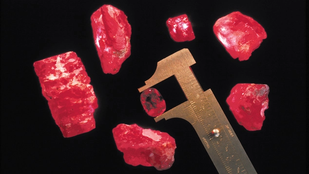 Frammenti grezzi di rubino rosso accanto a una scala dimensionale